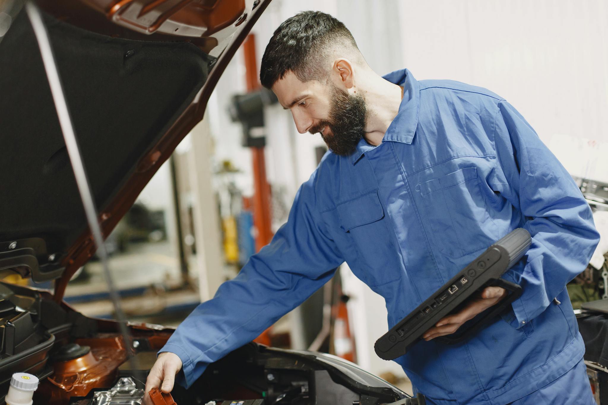 an auto mechanic in blue coveralls inspecting
