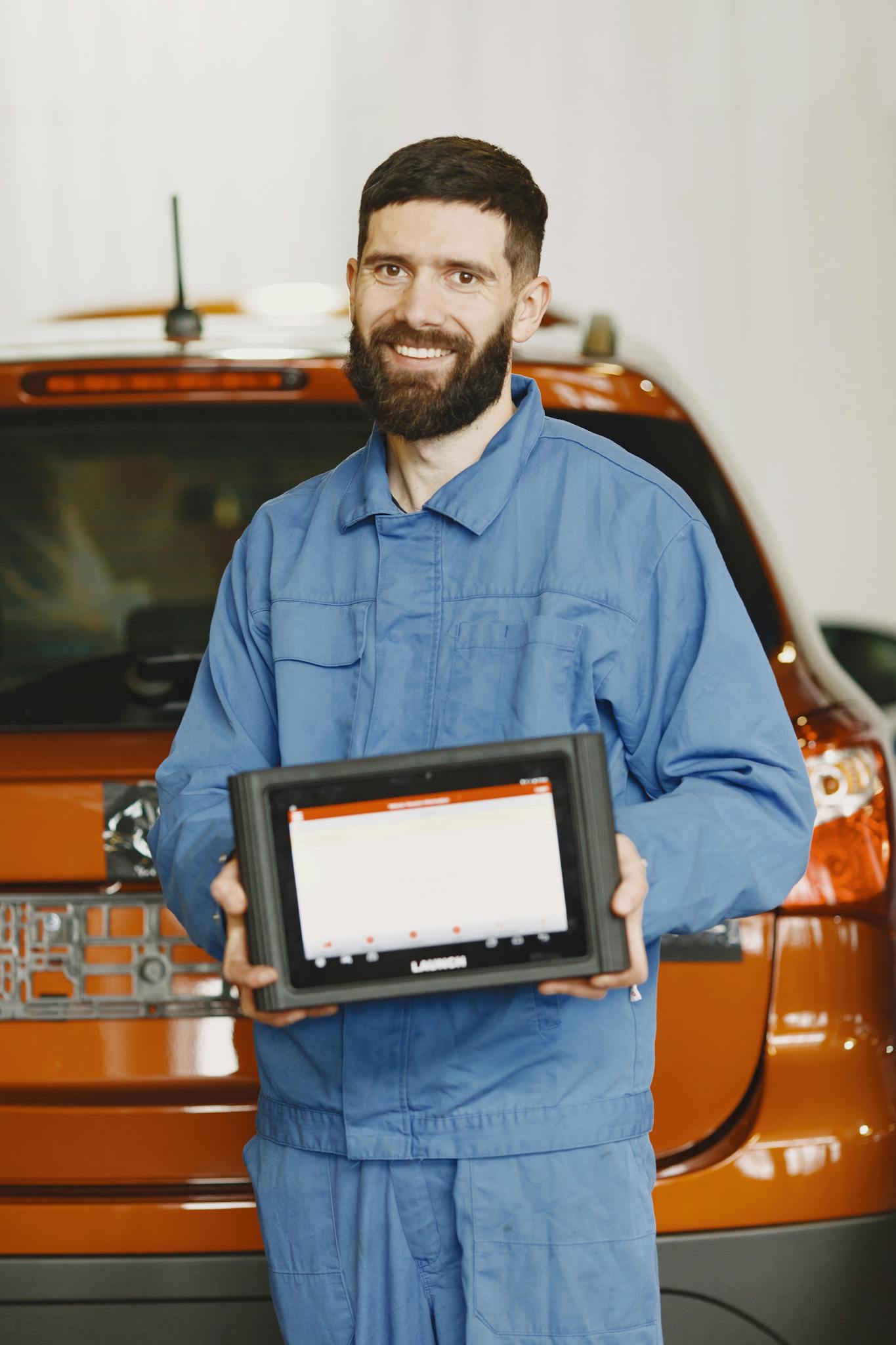 auto mechanic in blue coveralls holding a