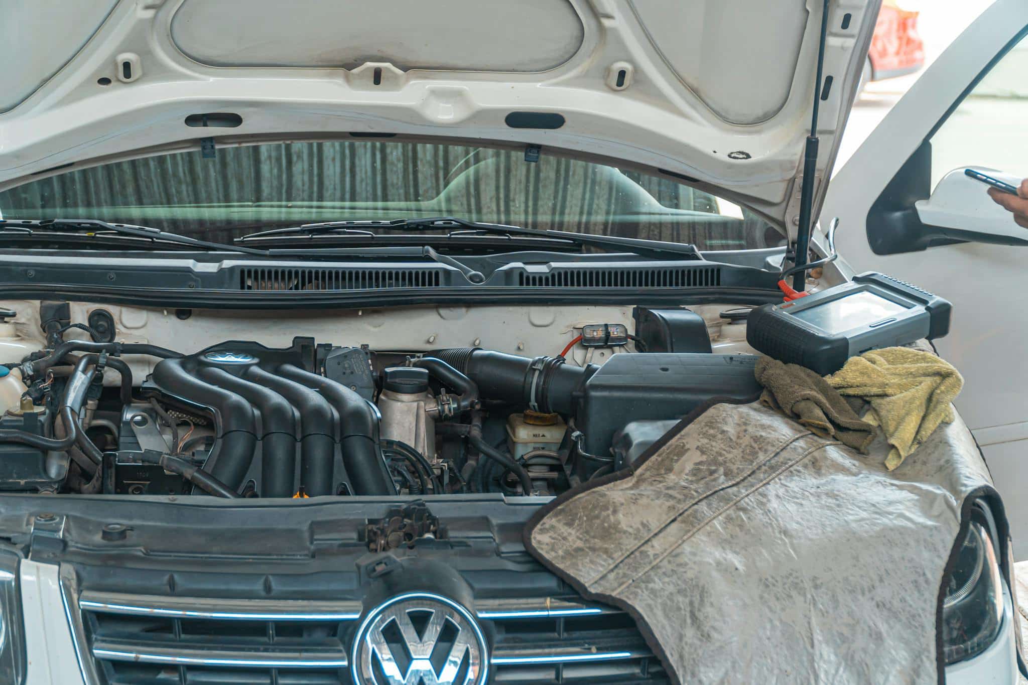 Close-up of a Volkswagen car engine undergoing repair in a garage, tools and diagnostic equipment in use.