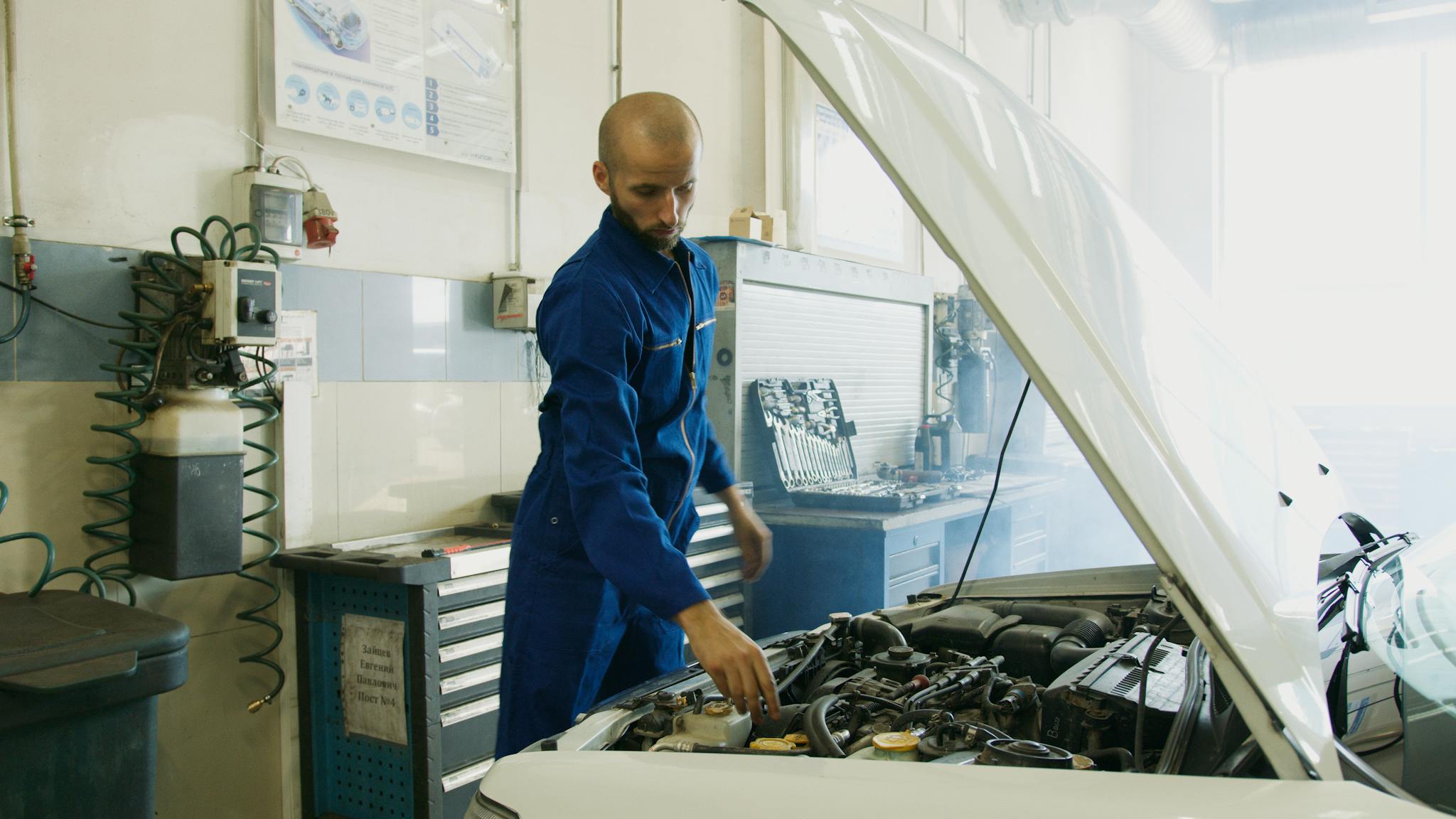 mechanic in blue uniform inspecting a car