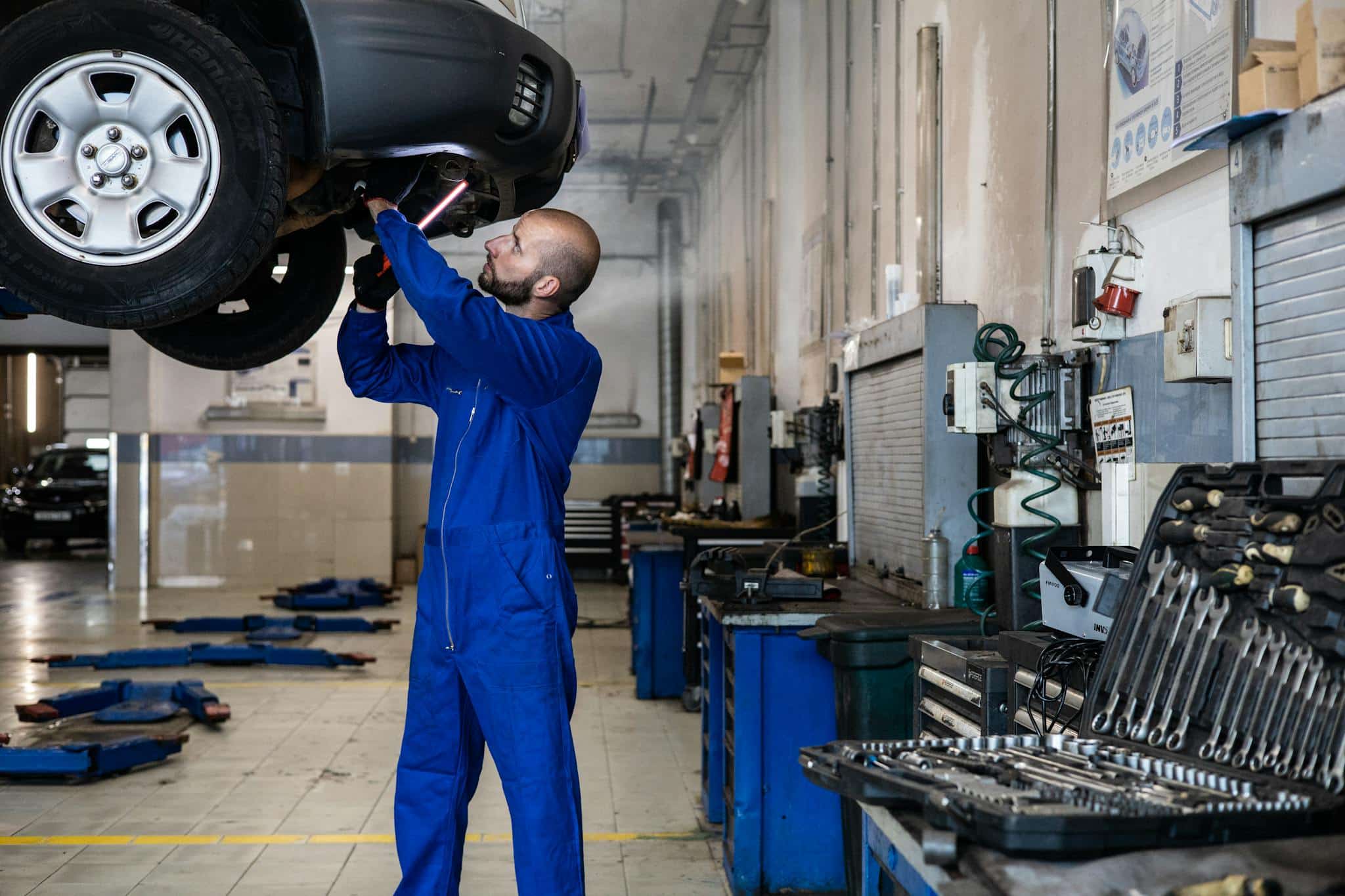 mechanic inspecting a raised car in an
